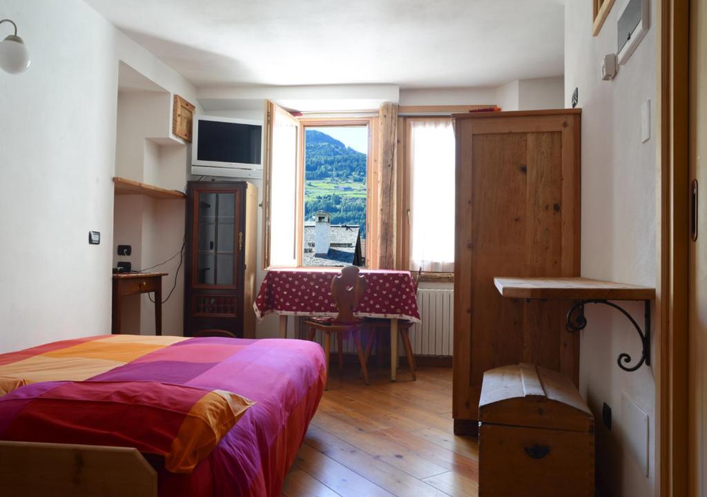 um quarto com uma cama, uma secretária e uma janela em premesan em Bormio