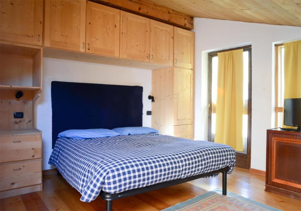 - une chambre avec un lit dans une pièce dotée d'armoires en bois dans l'établissement premesan2, à Bormio