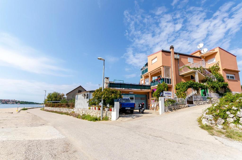 a building on the side of a road next to the beach at Apartments Nada in Rogoznica