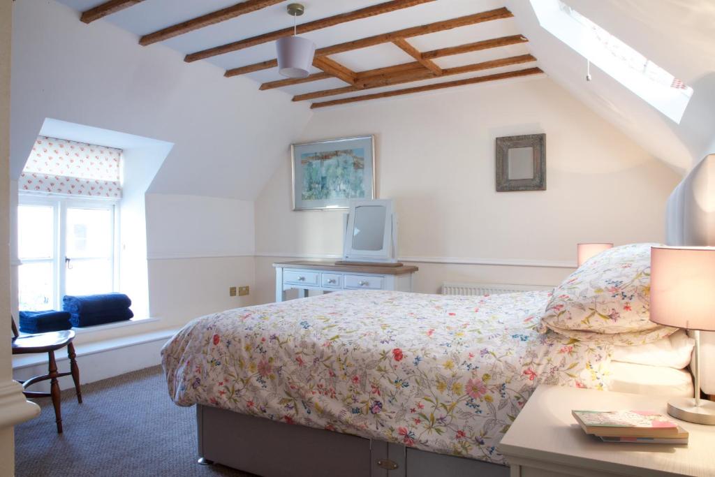 a bedroom with a bed and a desk and a window at Strawberry Cottage in Cheddar