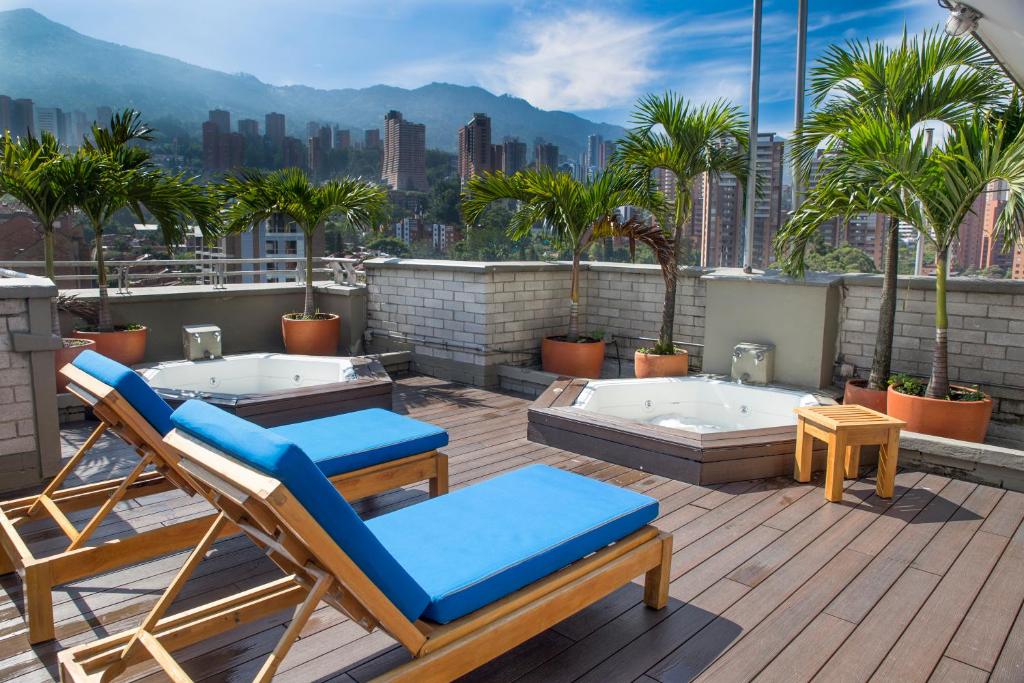 een patio met 2 ligstoelen en palmbomen op een dak bij Apartamentos Poblado Alejandría by HOUSY HOST in Medellín