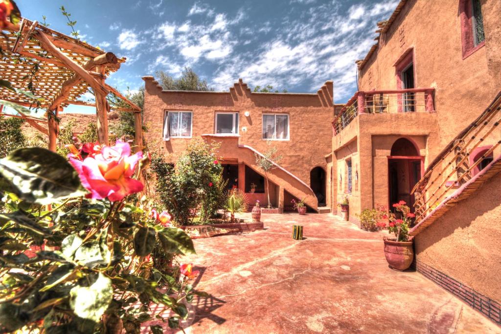 a large brick house with a courtyard with flowers at Jardin de la source in Aït Yous