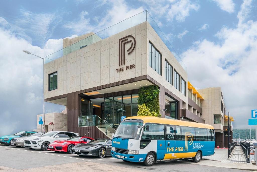 un autobus parcheggiato di fronte a un edificio con auto parcheggiate di The Pier Hotel a Hong Kong