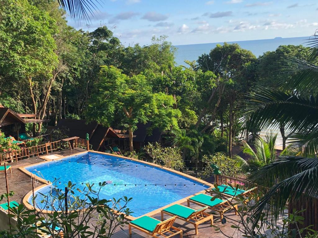 a swimming pool with chairs and the ocean in the background at Koh Jum Ocean Beach Resort in Ko Jum