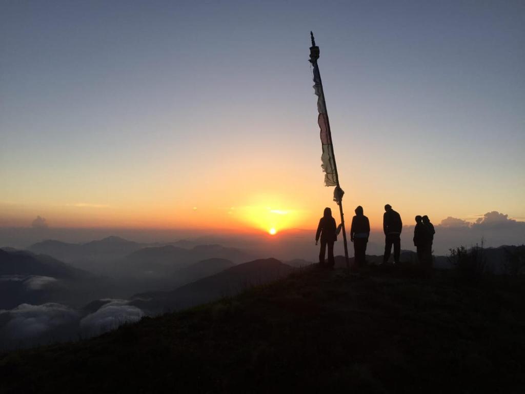 a group of people standing at the top of a mountain at sunset at Mount Mahabharat Homestay in Panaoti