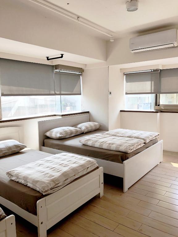 2 letti in una camera con 2 finestre di Ahiruyah Guesthouse a Kaohsiung