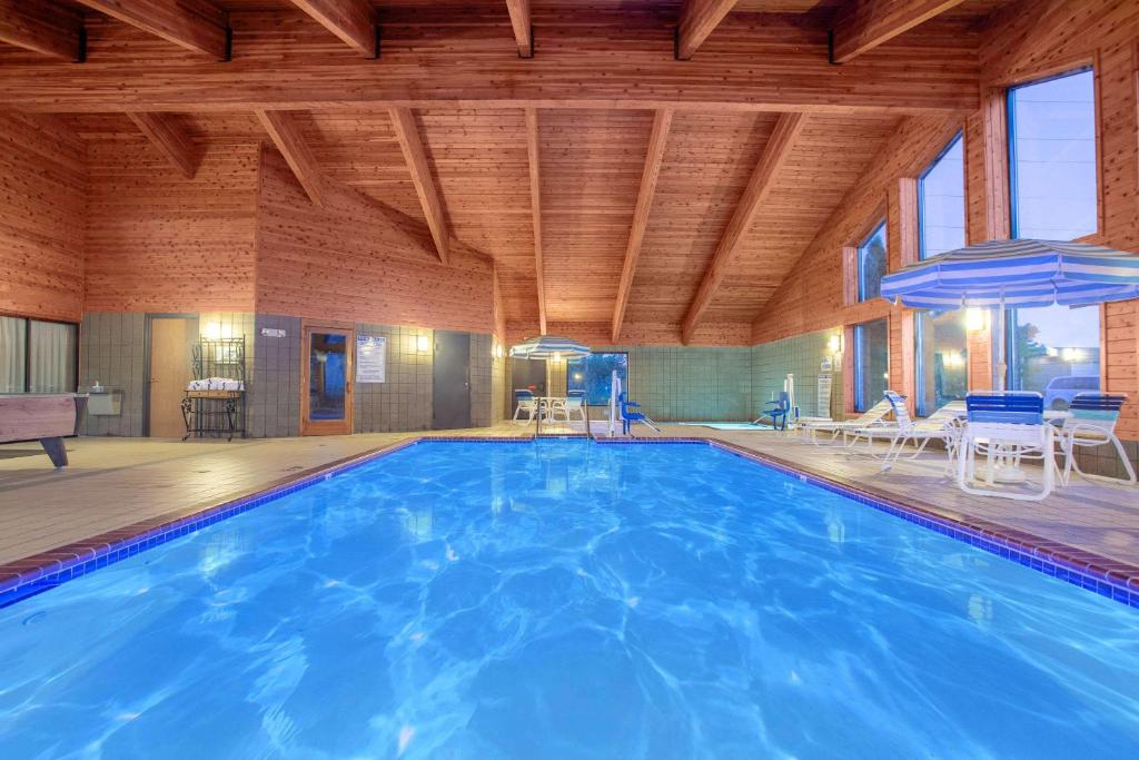 a large swimming pool in a house with a wooden ceiling at AmericInn by Wyndham Hayward in Hayward