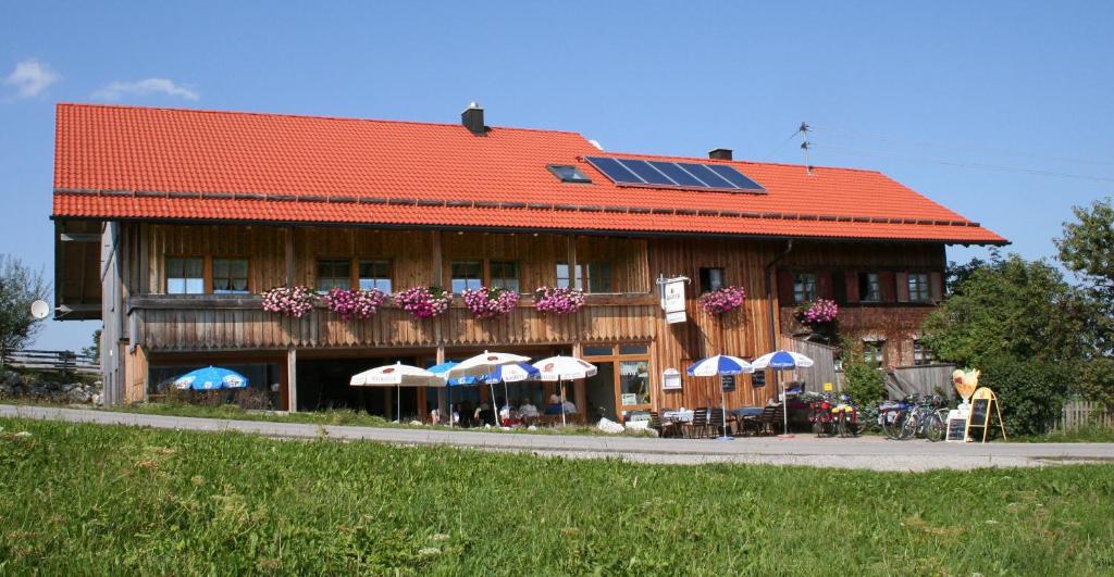 Maria Rain的住宿－阿爾穆凱菲斯納肯霍爾旅館，一座带太阳能屋顶的建筑,配有桌子和遮阳伞