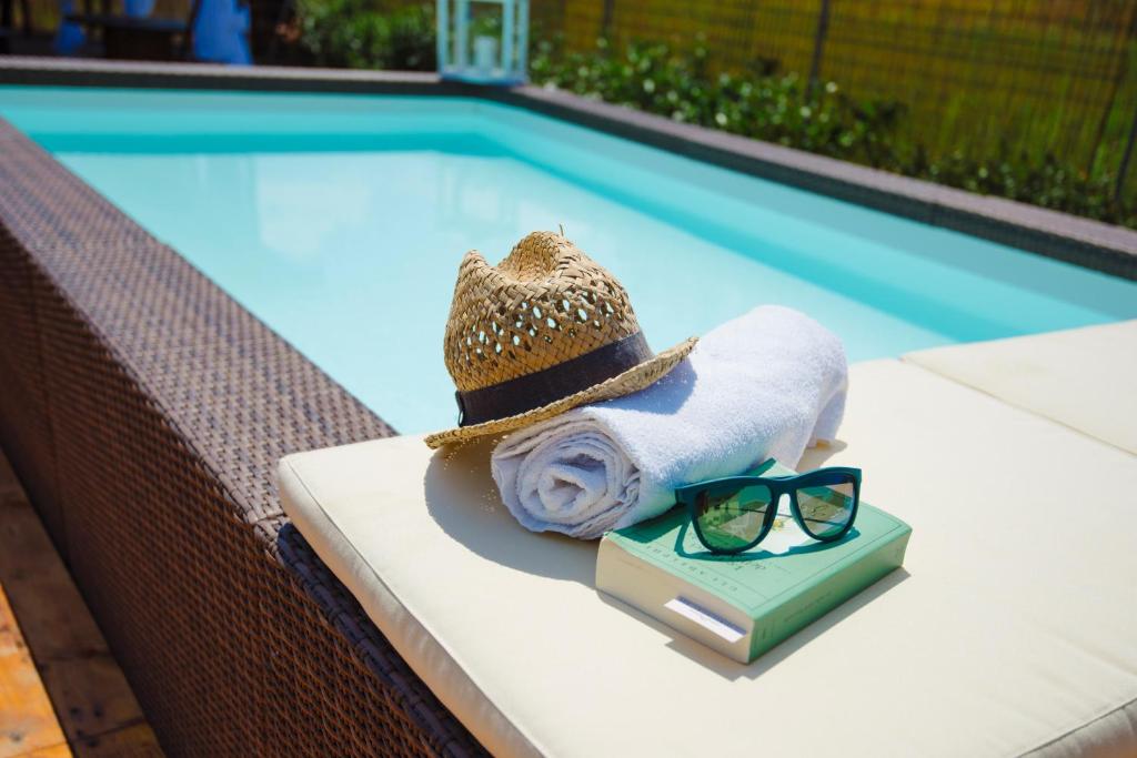 a hat and sunglasses sitting on a book next to a swimming pool at Dolce Sosta in Lucca