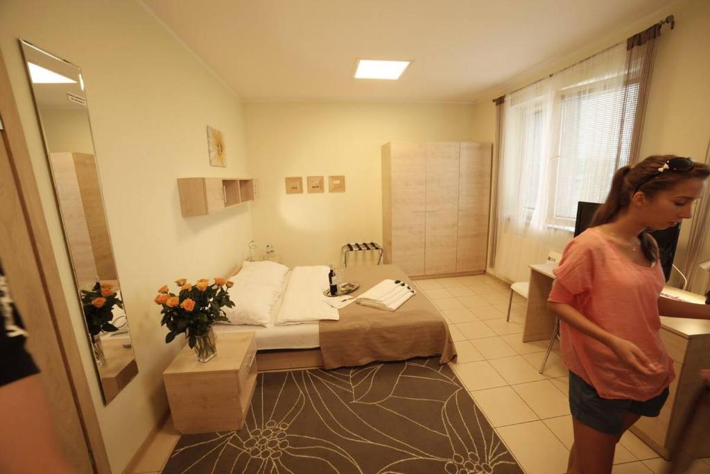 uma mulher em pé em frente a um quarto com uma cama em Standard Delegacyjny Bed & Breakfast em Dąbrowa Górnicza