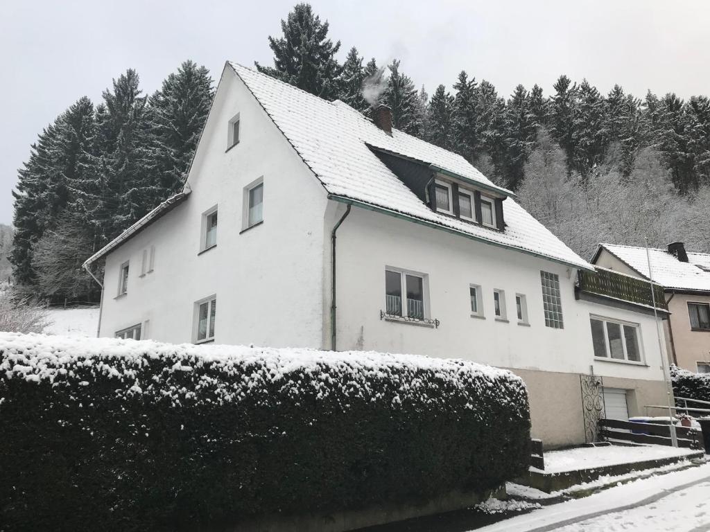 ein weißes Haus mit Schnee auf dem Dach in der Unterkunft Gruppenferienhaus Zum Rabenhorst für bis zu 16 Personen am Waldrand gelegen in Hallenberg