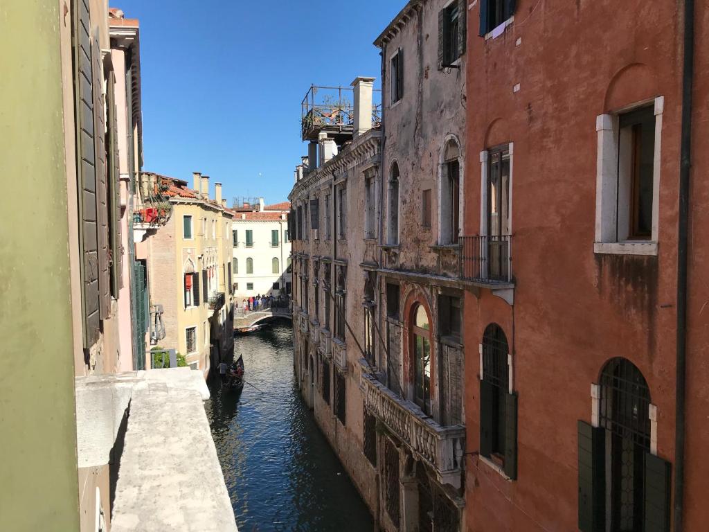 a canal between two buildings in a city at Luxury Venetian Rooms in Venice