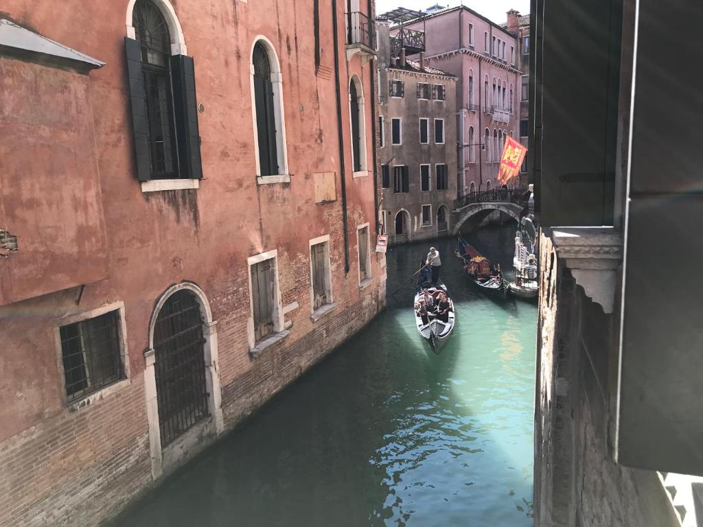 a boat in a canal between two buildings at Luxury Venetian Rooms in Venice