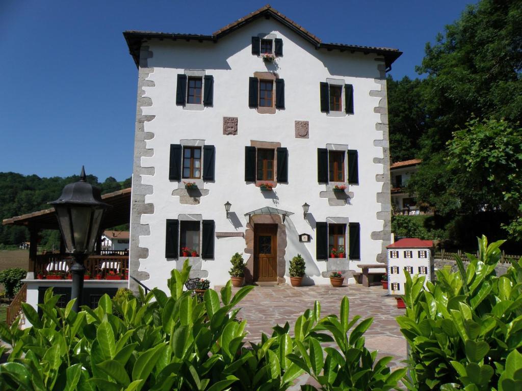 una gran casa blanca con persianas negras en Hotel Rural Irigoienea, en Urdax