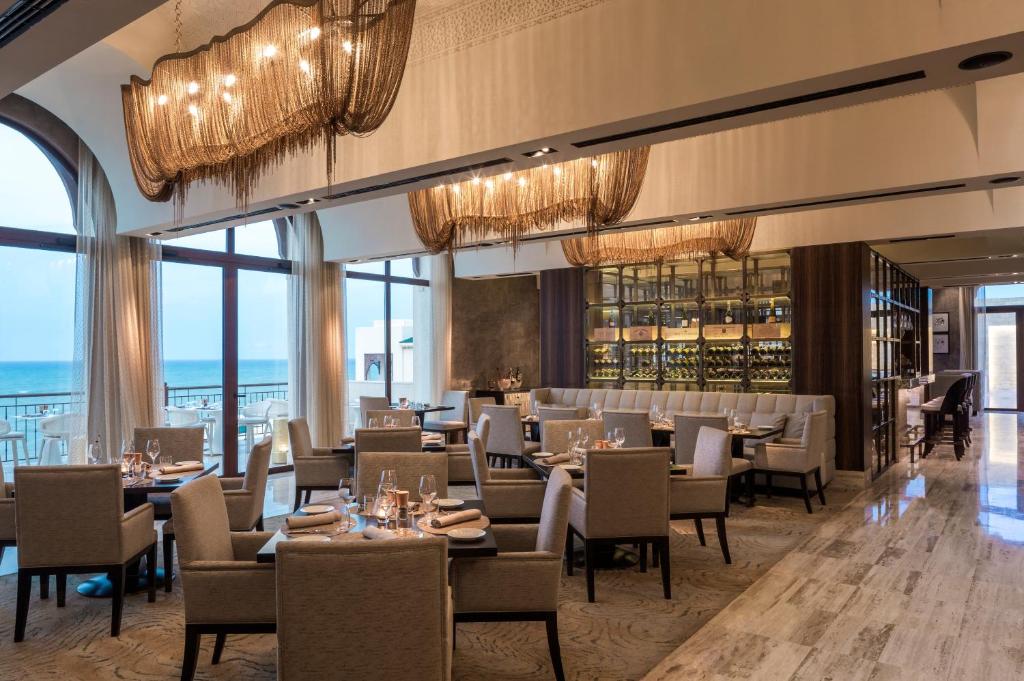 a dining room with tables and chairs and chandeliers at Four Seasons Hotel Tunis in Gammarth