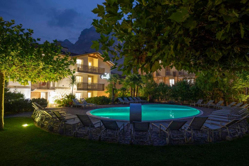 a pool in a yard with chairs and a building at 4 Limoni Apartment Resort in Riva del Garda