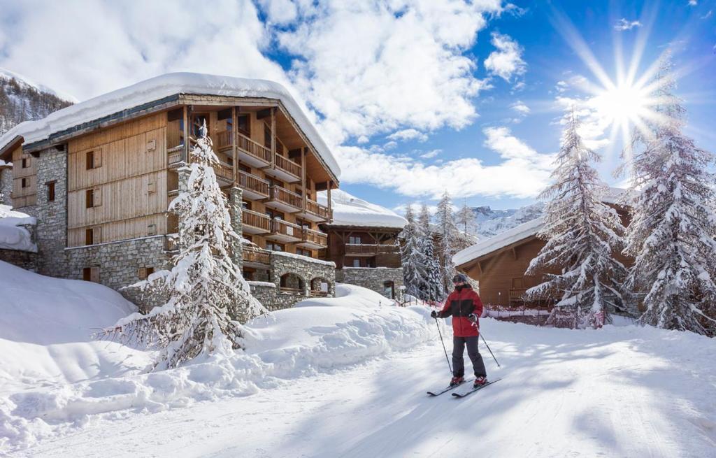 une personne à skis dans la neige devant un lodge dans l'établissement Les Chalets Du Jardin Alpin, à Val dʼIsère