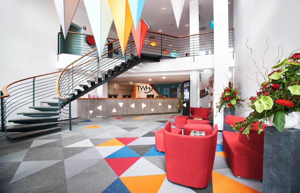 a lobby with a staircase and a colorful floor at Trans World Hotel Donauwelle in Linz