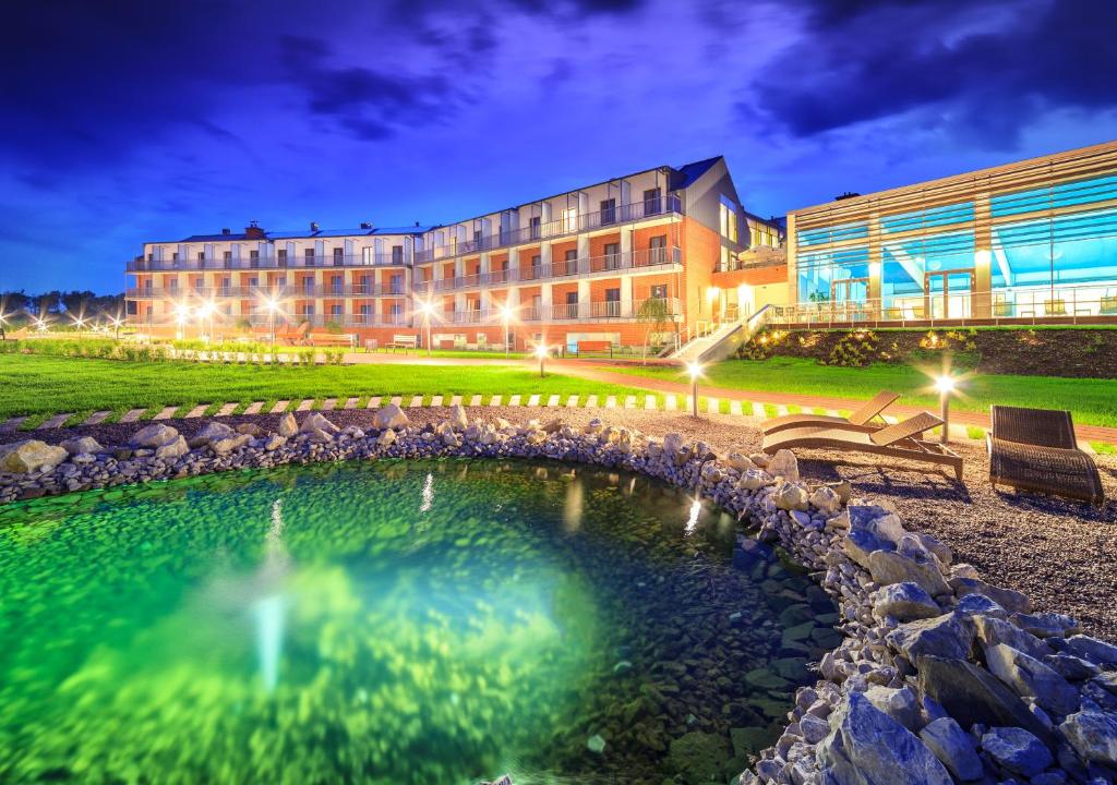 a building with a pond in front of a building at Słoneczny Zdrój Medical Spa & Wellness in Busko-Zdrój