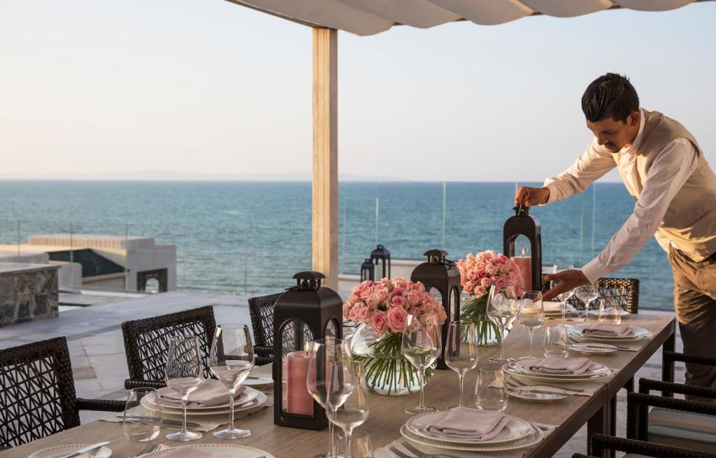 a man is setting a table on the beach at Four Seasons Hotel Tunis in Gammarth