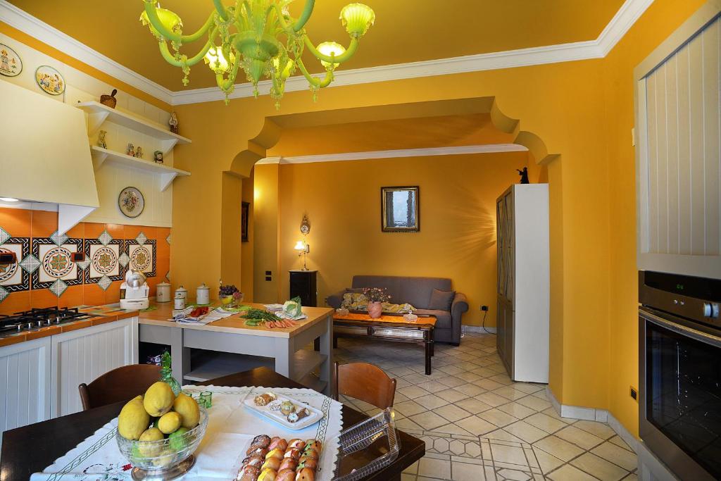 cocina y sala de estar con paredes amarillas y mesa. en Donna Filomena Casa Vacanza di Charme, en Salerno