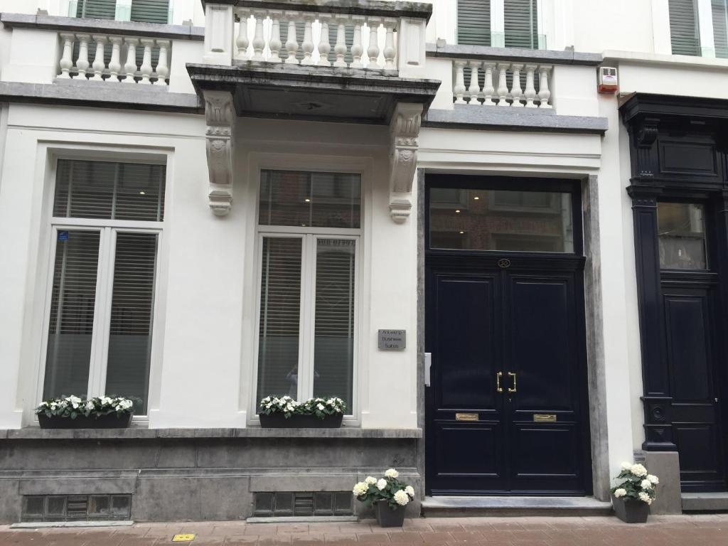 a white house with black doors and windows at Antwerp Town House Accommodations in Antwerp