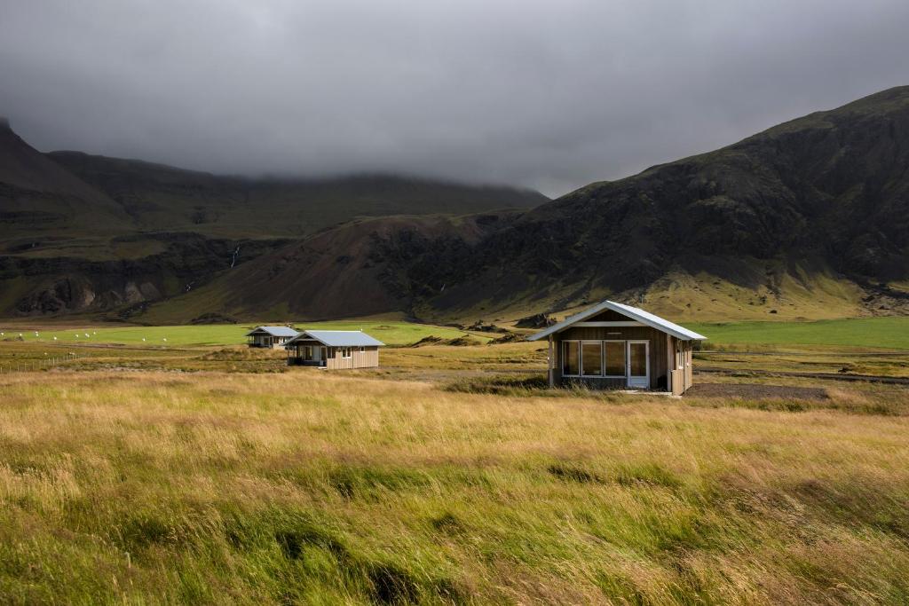 Deux maisons dans un champ avec des montagnes en arrière-plan dans l'établissement Myllulækur, à Nesjum