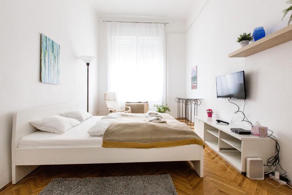 een witte slaapkamer met een bed en een bureau bij Home in the living Budapest in Boedapest
