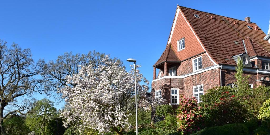 ceglany dom z kwitnącym drzewem przed nim w obiekcie Ferienwohnung am Ostseebad w mieście Flensburg