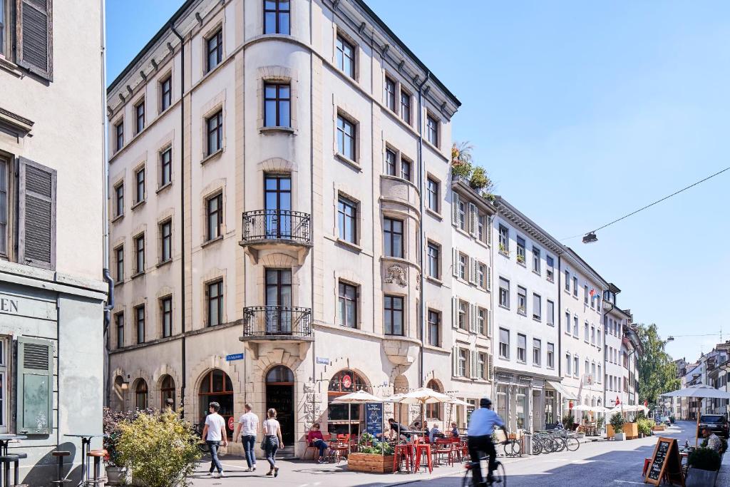 a large white building with people walking on a street at Consum Boutique Hotel in Basel