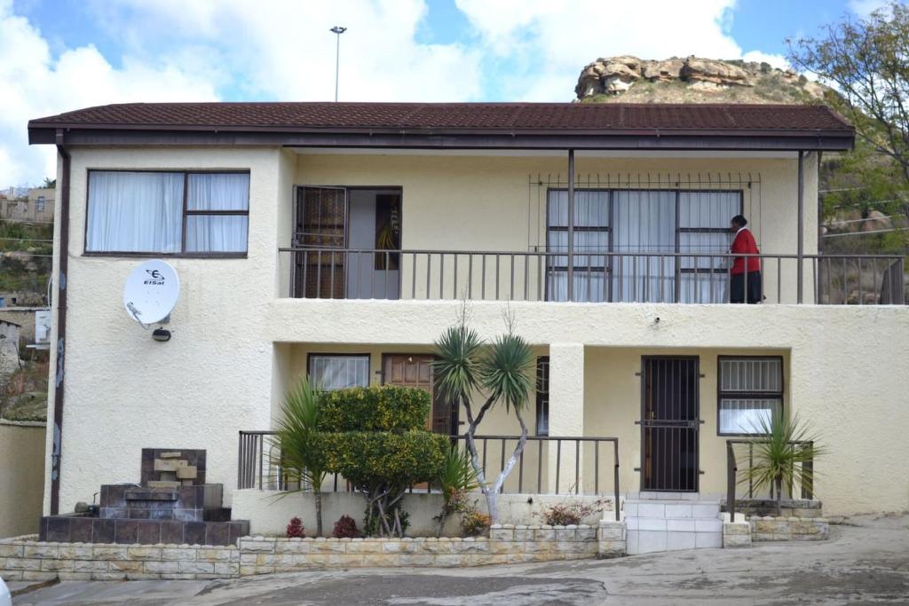 un hombre parado en el balcón de una casa en City Stay en Maseru