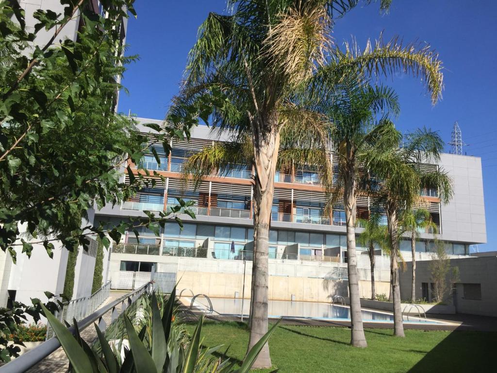 un edificio con palmeras delante en Loft with terrace 24m2, swimming pool and garage en Chirivella