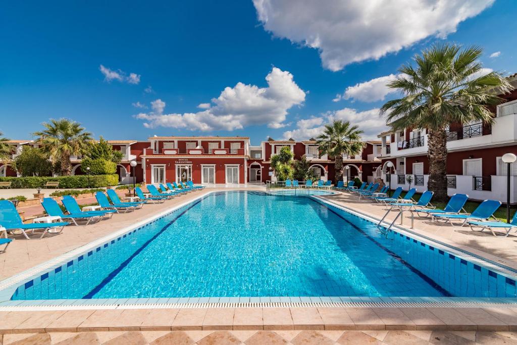 拉加納斯的住宿－Yakinthos Hotel，一座带椅子和棕榈树的游泳池以及一座建筑