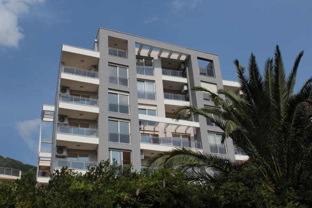 an apartment building with a palm tree in front of it at Olimp Lux in Budva