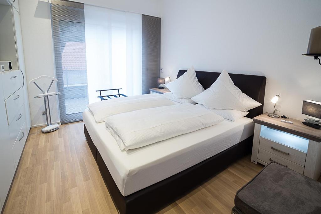 Schlafzimmer mit einem großen Bett mit weißer Bettwäsche und einem Schreibtisch in der Unterkunft Premium Business Apartment in Oberkochen in Oberkochen