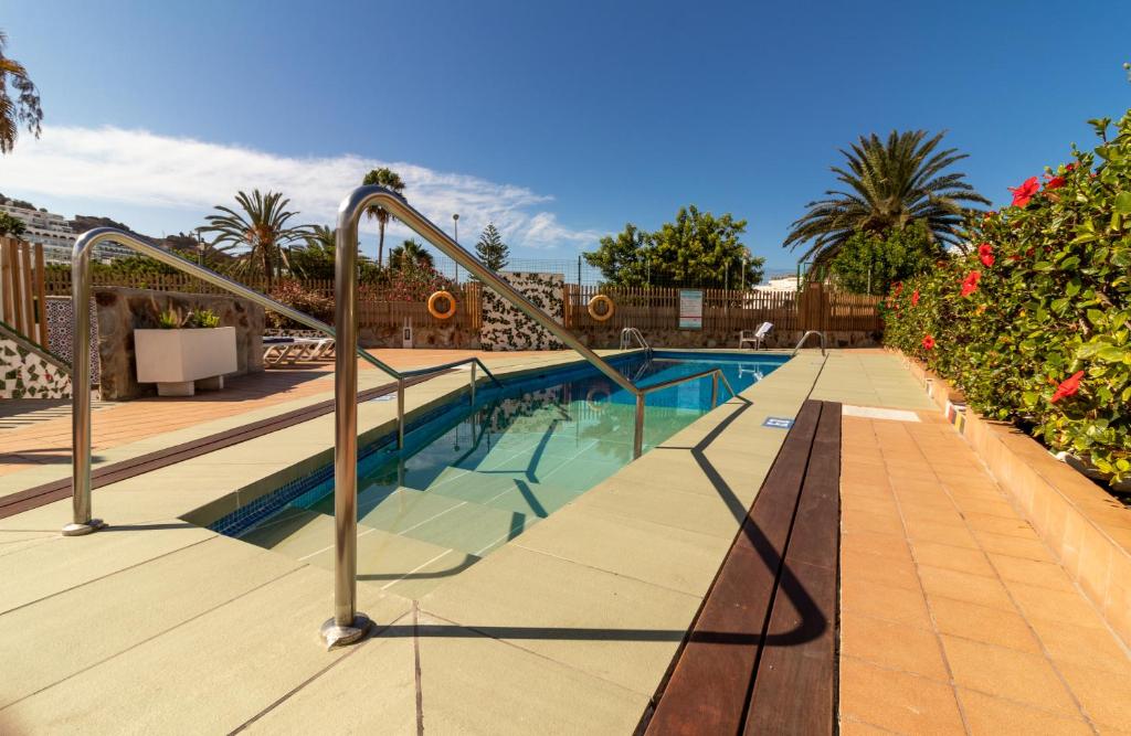 a swimming pool with metal hand rails in a resort at Leticia del Mar Adults Only in Puerto Rico de Gran Canaria
