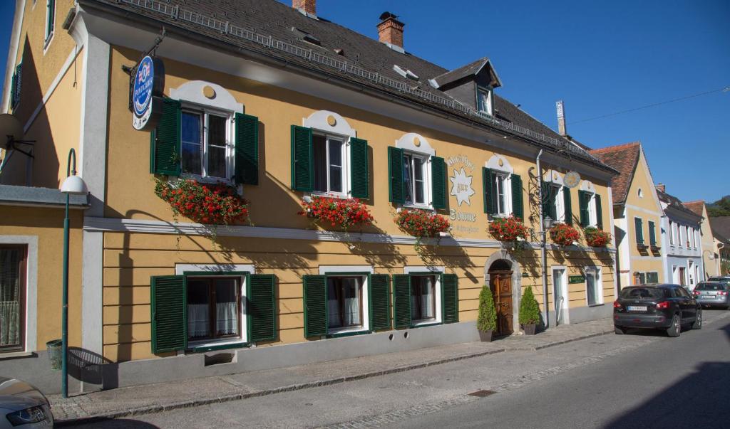 ein Gebäude mit grünen Fensterläden und Blumen auf einer Straße in der Unterkunft Gasthof zur Sonne in Übelbach