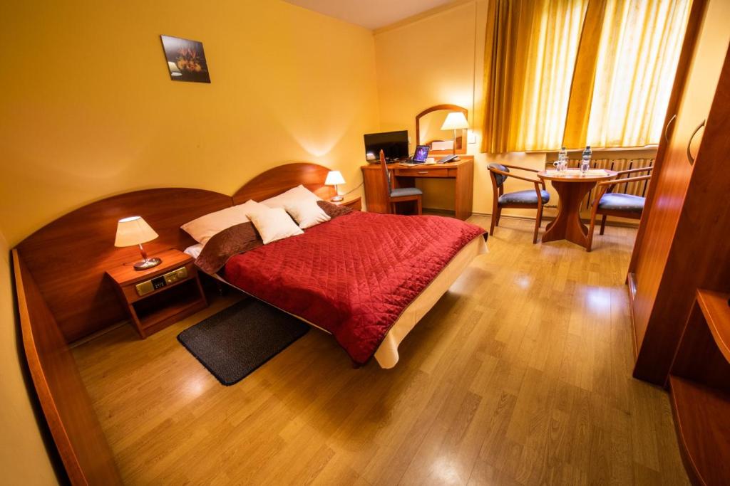 een hotelkamer met een bed, een bureau en een tafel bij Hotel Wald in Warschau