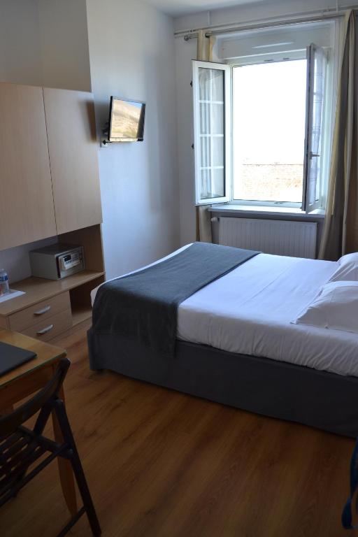 a bedroom with a bed and a window and a table at Hôtel La Porte Saint Pierre-Logis Hôtel Intra Muros in Saint Malo