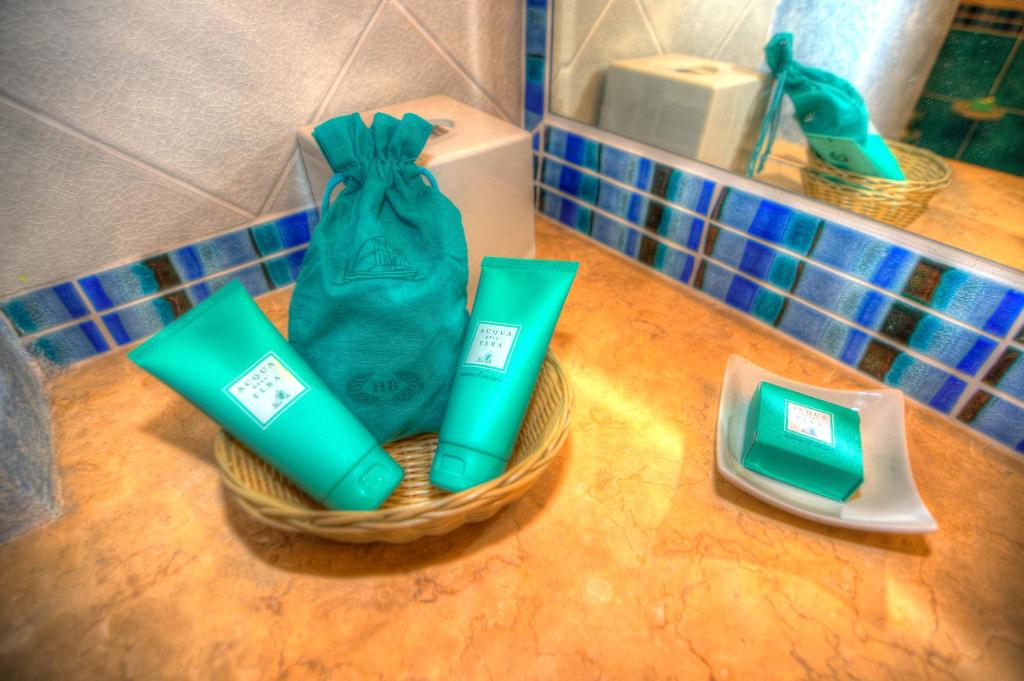 two green toothbrushes and a bag on a counter at Hotel Biodola in Portoferraio