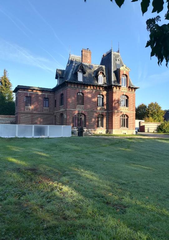 un vieux château avec une pelouse devant lui dans l'établissement Chateau Gruchet Le Valasse, à Gruchet-le-Valasse