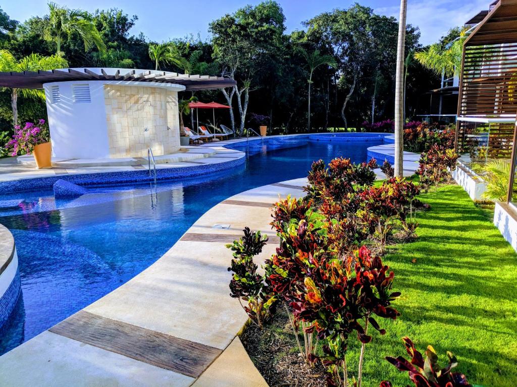 una piscina con agua azul y flores en un patio en Bahia Principe & Golf Residences (Terrazas Condo) en Tulum