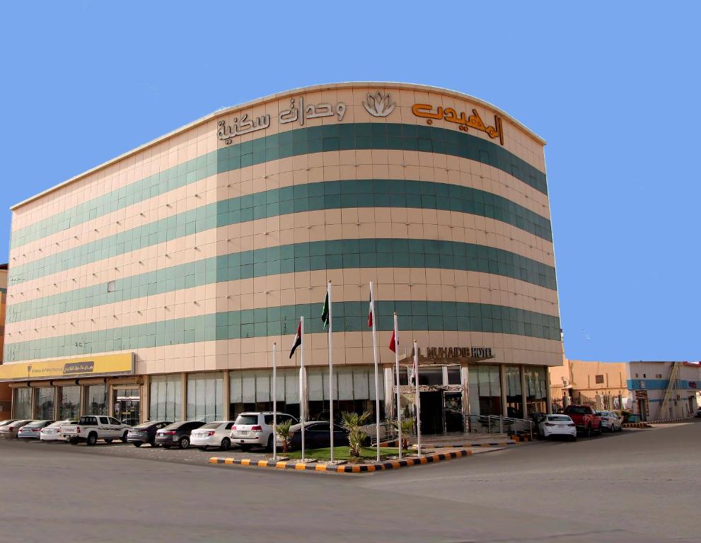 ein großes Gebäude mit Autos auf einem Parkplatz in der Unterkunft Al Muhaidb Residence Al Dowally in Hafar Al-Batin