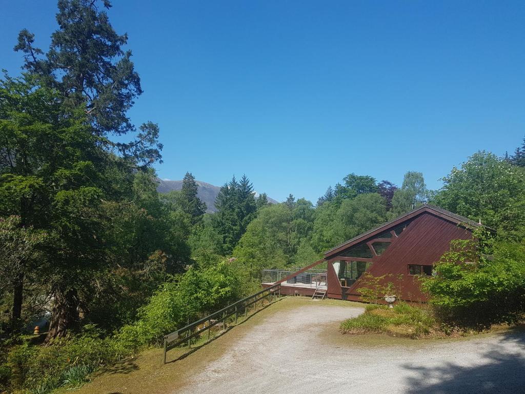 a bridge over a dirt road next to a forest at Invergloy Riverside Lodges in Spean Bridge