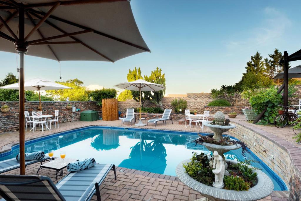 a pool with an umbrella and a fountain at Shawheim@Hartenbos in Hartenbos