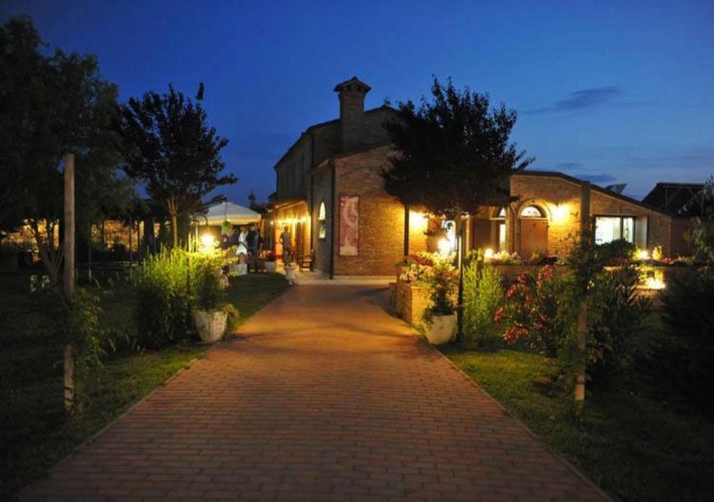 a brick pathway leading to a house at night at Agriturismo Alla Strozza in Voghenza