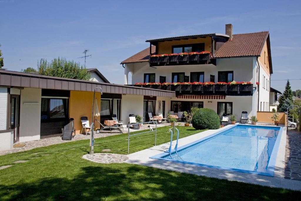 a villa with a swimming pool in front of a house at Parkpension Billroth in Bad Hall