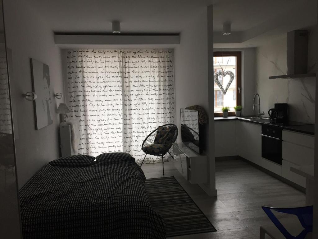 a bedroom with a bed and a kitchen with a window at Apartament blisko starówki, Apartment near to old town in Gdańsk