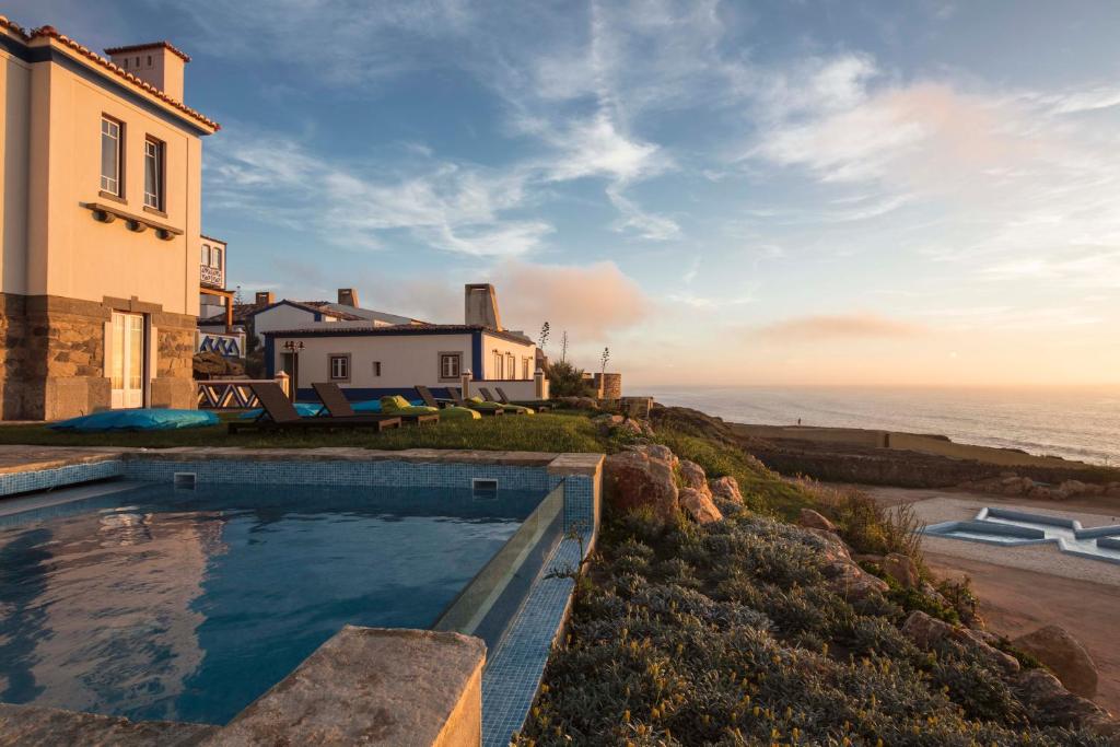 a house with a swimming pool next to the ocean at Chalet O Amorzinho Sintra Praia in Sintra