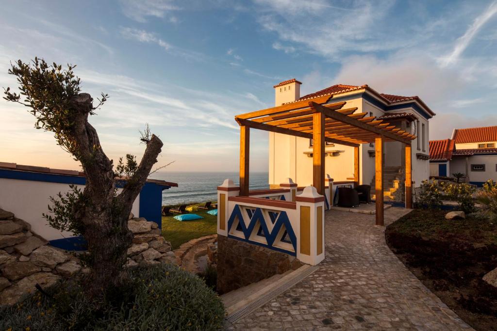 a house with a gazebo next to the ocean at Chalet O Amorzinho Sintra Praia in Sintra